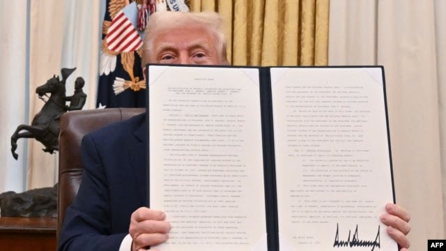 Presiden AS Donald Trump menunjukkan lembar Instruksi Presiden yang ia tandatangani. (Foto : AFP)